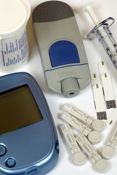 Home Diabetes self-test kit including glucose test strips, sharp lancets, syringe, and glucometer.
