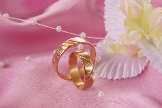 wedding golden rings with decoration on pink satin