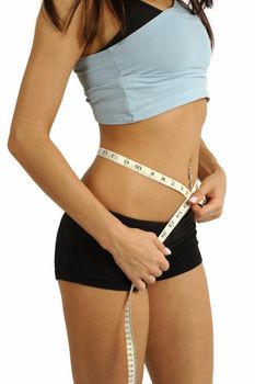 A tanned slim young woman measuring her waistline.
