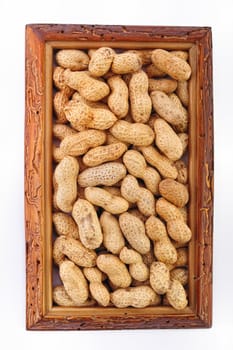 Unshelled nuts in a wooden frame on white background