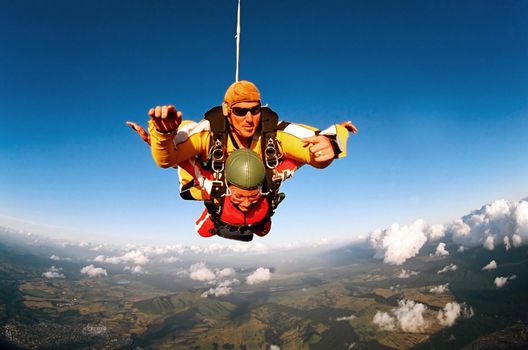 Tandem skydiver in action parachuting, seen in mid air position.