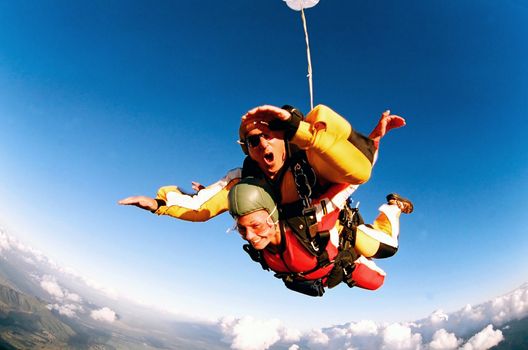 Tandem skydiver in action parachuting, seen in mid air position.