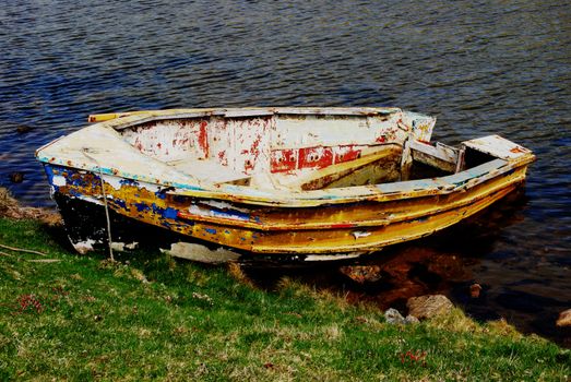 old boat tied on a coastline with a leak