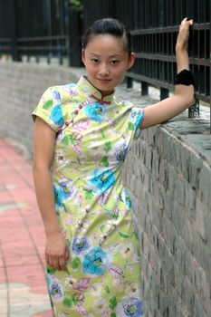 Chinese girl standing on side walk, wearing traditional Chinese dress - qipao.