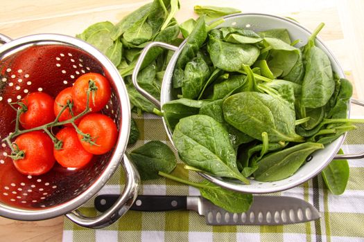 Fresh spinach leaves with tomatoes on cutting board