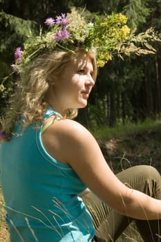 Young beautiful blonde in a forest with flowers diadem