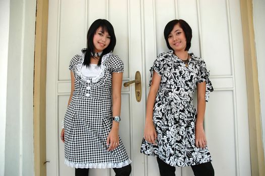 two sisters get posed in front of an old door