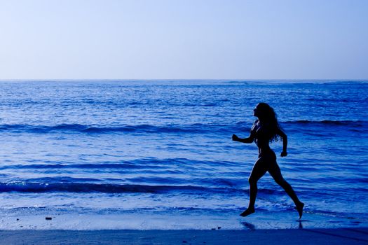 Healthy life concept - sporty woman running along beach in the morning