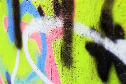 A close up photograph of brightly coloured graffiti on a textured concrete wall