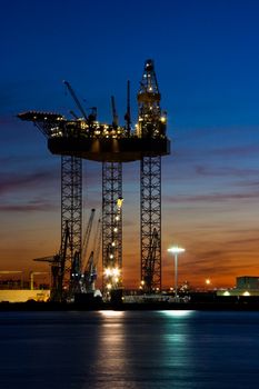 Big drilling platform in repair in the harbour at sunset