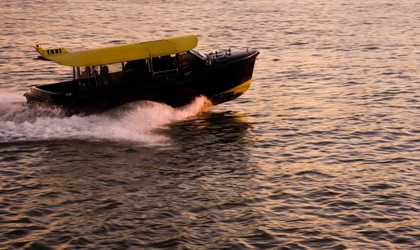 Water taxi passing by on the river with fast speed at sunset