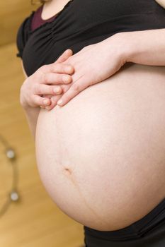 Pregnant woman holding belly with arms 8 month