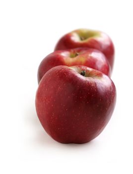 Row of red apples on a white background 
