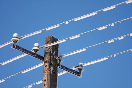 Frozen telephone lines with clear blue sky as background