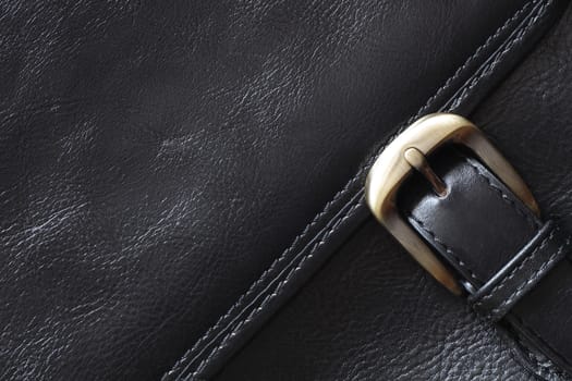 Extreme closeup of black leather briefcase with brass buckle