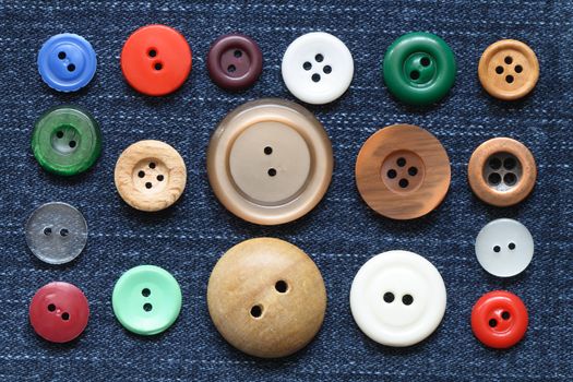 Set of various buttons lying on jeans textured background