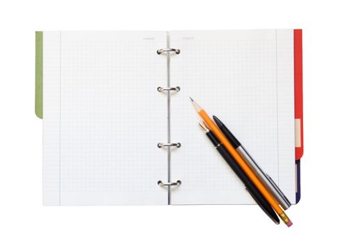 Two pens and wooden pencil lying on open spiral notebook. Isolated with clipping path