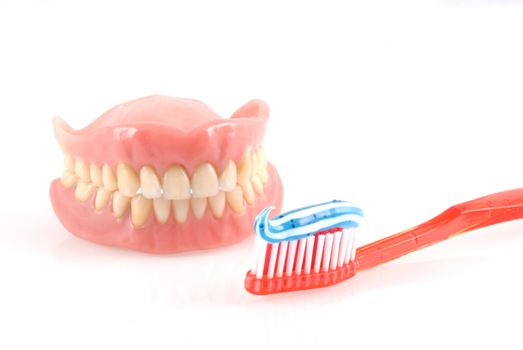Dentures and toothbrush with toothpaste isolated on white.