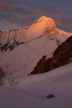 Huandoy mountain at sunrise with a lone tent in foreground, Cordillera Blanca, Peru.