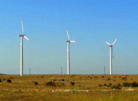 three windmills in a green field and blue sky in the background