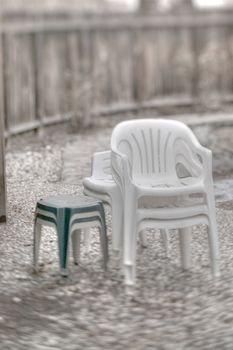 Plastic furniture put away for winter, poolside on a patio.