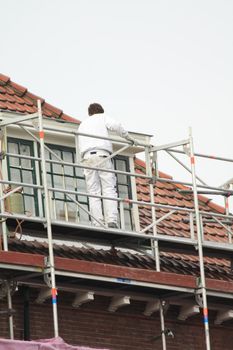 A painter working on a roof high scaffold