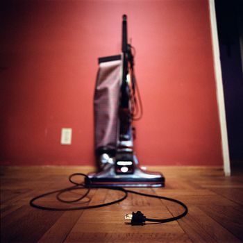 Early model upright vacuum with electrical cord in the foreground.