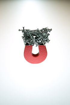 A small magnet with  a stack of brads demonstrating attraction