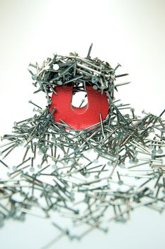 A small magnet with  a stack of brads demonstrating attraction