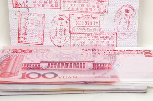 Passport full of stamps from China and Hongkong borders together with Chinese money, RMB banknotes.