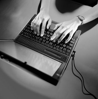 Woman using an old notebook computer with the power cord attached.