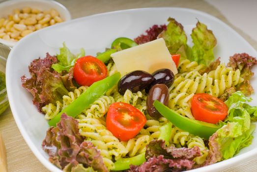 fresh healthy homemade italian fusilli pasta salad with parmesan cheese,pachino cherry tomatoes, black olives and mix vegetables ,dressed with extra-virgin olive oil and pesto sauce