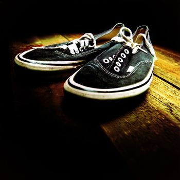 Vintage sneakers with black canvas tops on aged deck wood.