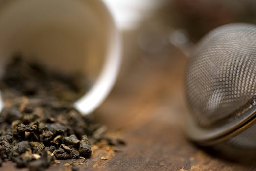 dry green chinese tea set,with strainer closeup,cups and teapot on background over old wood board