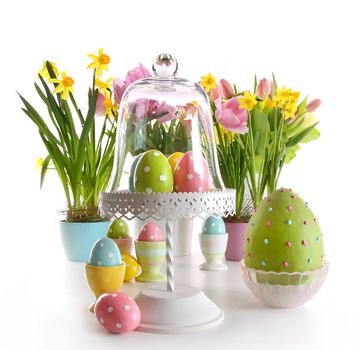 Easter eggs on cake stand with spring flowers on white