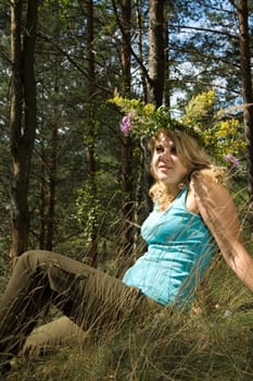 Young beautiful blonde in a forest with flowers diadem