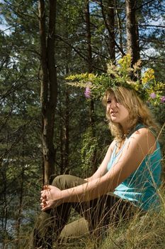 Young beautiful blonde in a forest with flowers diadem