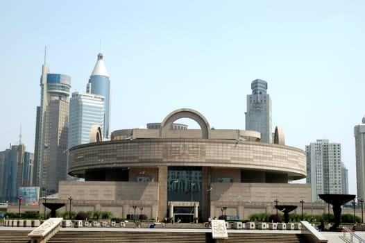 China, Shanghai city. General view of biggest museum in Shanghai with skyscrapers in background. Original building designed in round shape.