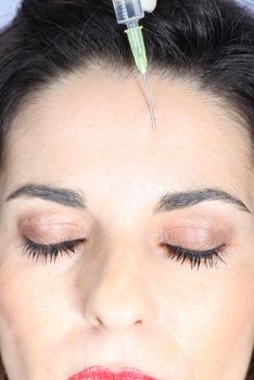 Young woman receives botox injection in her forehead - Close-up