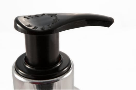 Close and low level capturing a black plastic pump dispenser arranged over white.