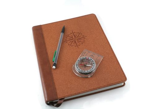 A brown travel journal imprinted with a compass and pencil, isolated on white.