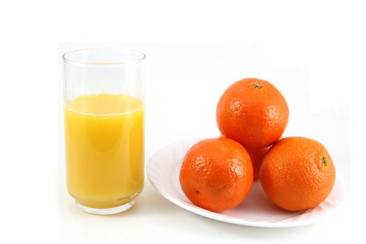 Glass of orange juice with oranges on the side.
