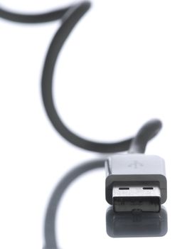 An USB connection facing camera with its cable curling and reflecting behind out of focus.