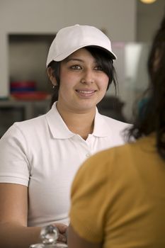 Young counter service girl taking an order from another young girl in a casual service restaurant.