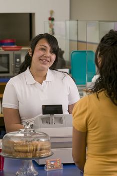 Young counter service girl taking an order from another young girl in a casual service restaurant.