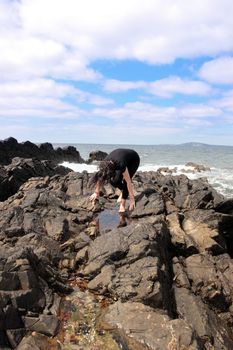 a beautiful woman feeling free on the rocks in ireland as the waves roll in