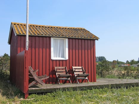 Cute little red summerhouse by the sea