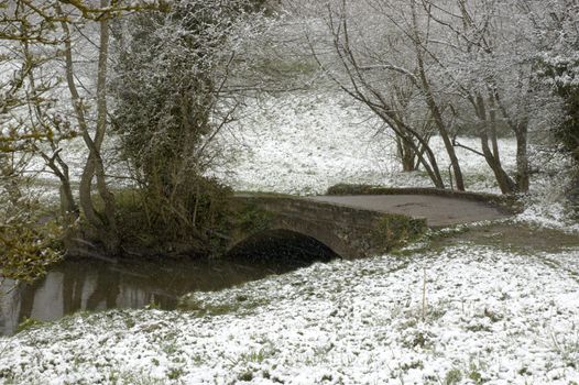 An arch bridge over a stream in winter