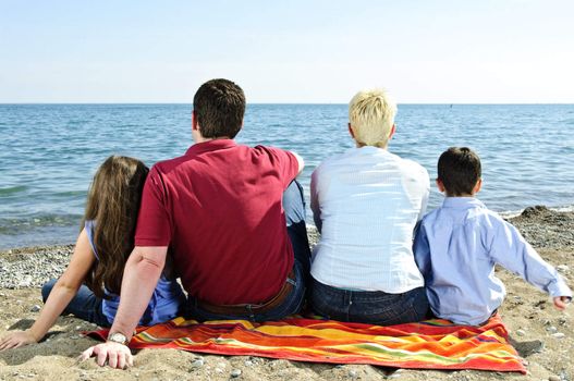 Family sitting on towel at sandy beach