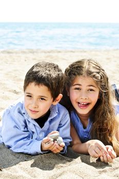 Portrait of brother and sister playing in sand at the beach